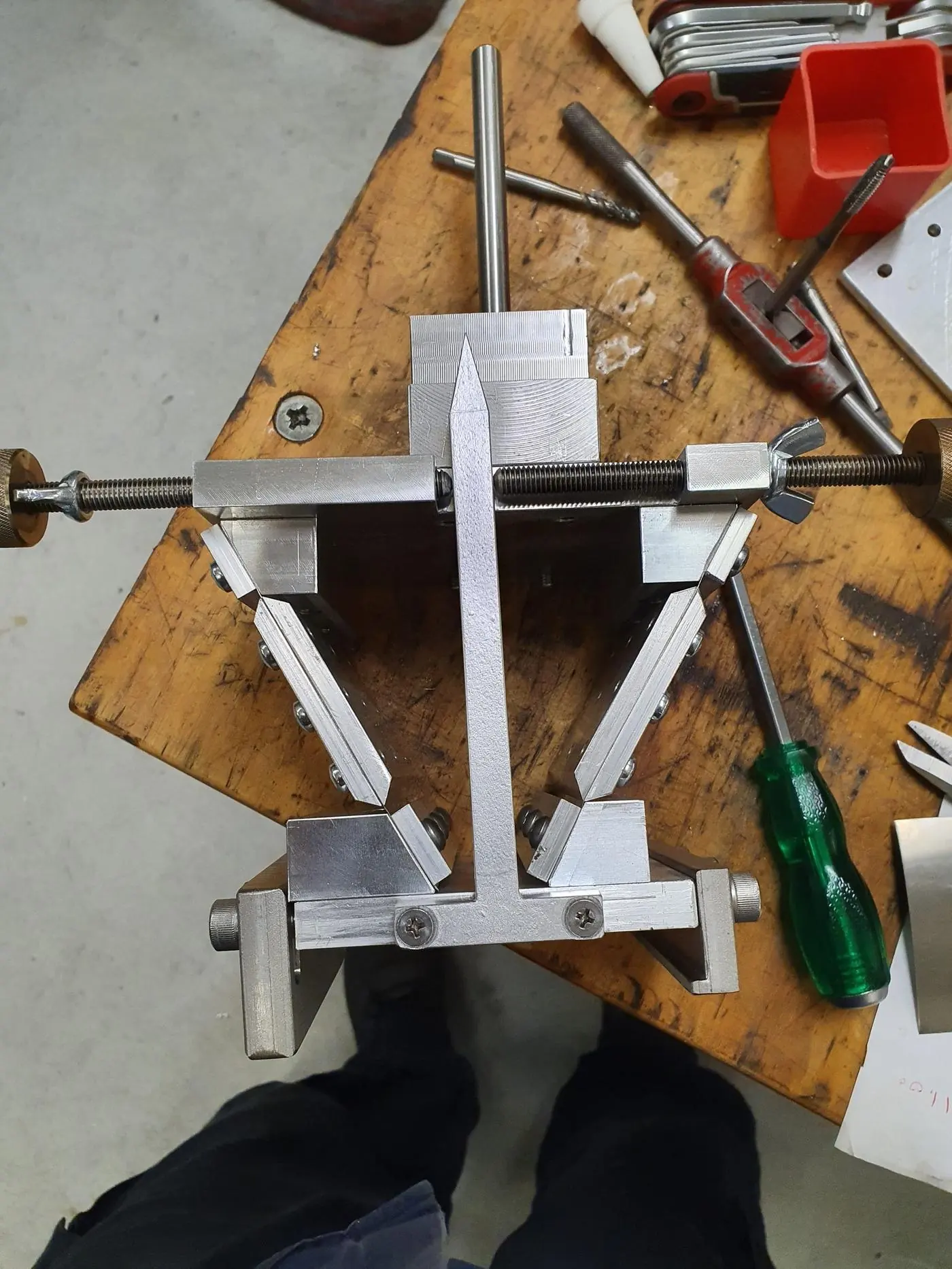 A machined aluminium jig on the bench