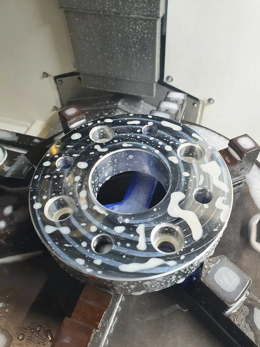 An aluminium hub being machined under coolant